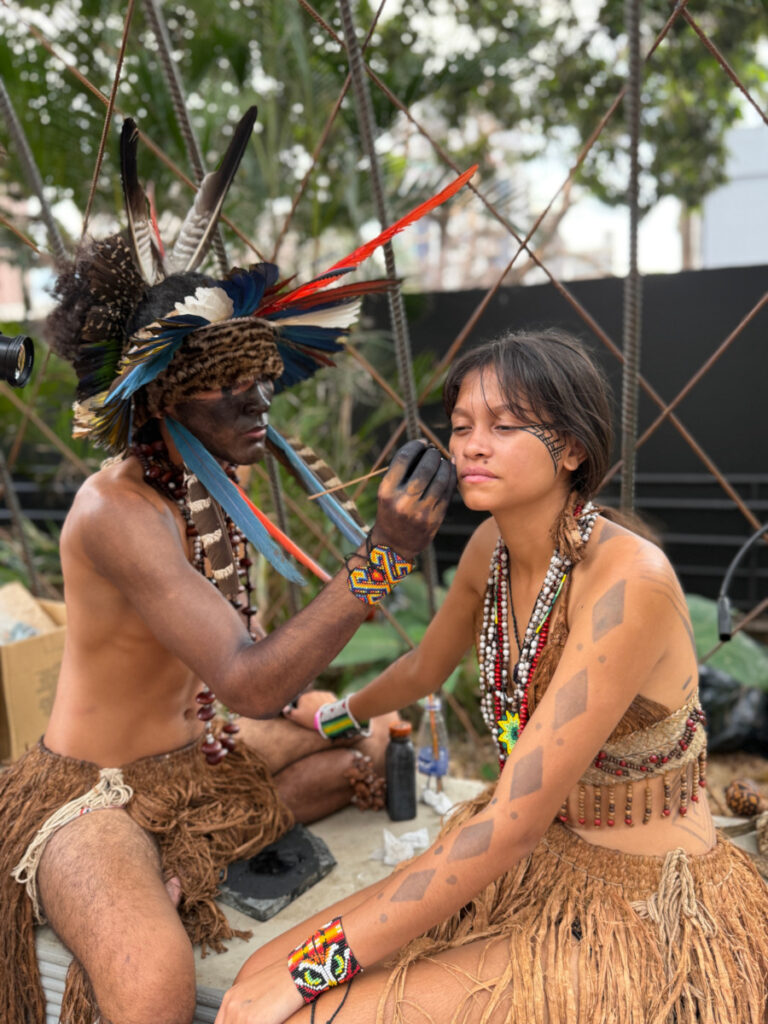 Indígenas da tribo Pataxó no Brasil pintando o corpo na exposição Casa Cor Minas 2026.